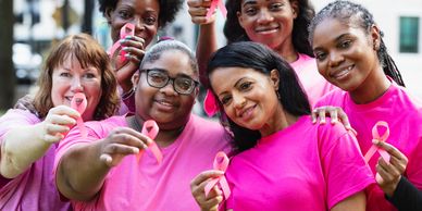 Group of women wearing pink and holding pink ribbons.