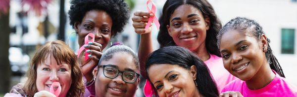 Group of women holding pink ribbons for breast cancer awareness.