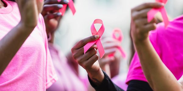 People holding pink ribbons for breast cancer awareness.