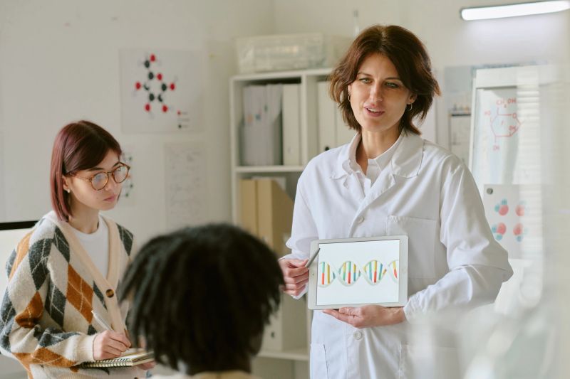 Scientist explaining genetic research to students in modern laboratory. Showing DNA structure on tablet, fostering collaborative learning environment