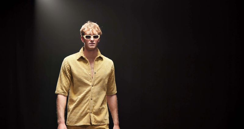 Fashion, runway and walking with man in studio for designer showcase, clothes presentation and event. Wardrobe launch, luxury brand and collection with model on stage with black background space