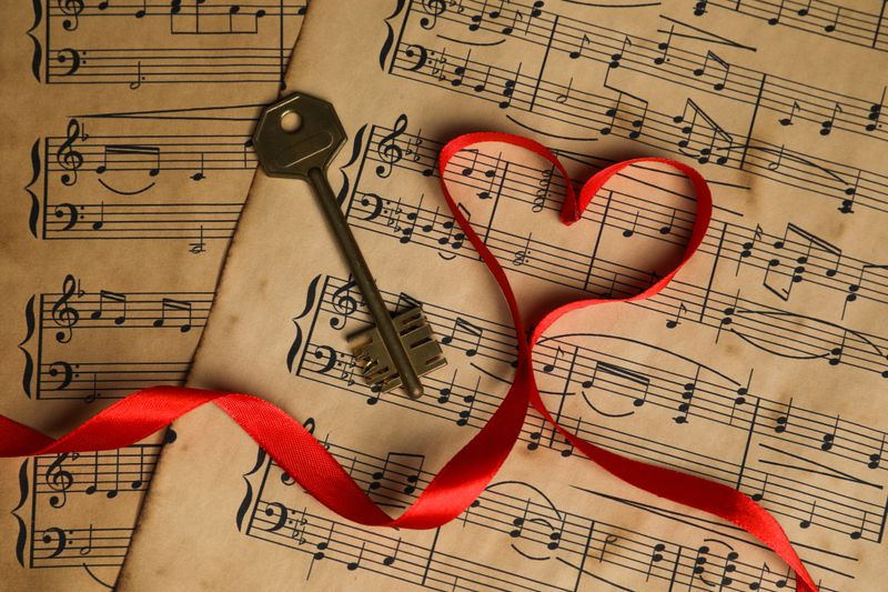 Key and heart shaped ribbon on musical notes, closeup