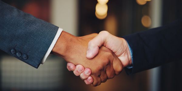 Two people in business suits shaking hands in agreement.