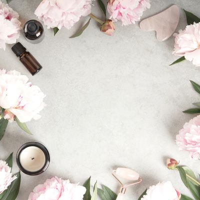 Flat lay of pink flowers and wellness tools on a light background.