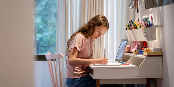 Teen girl studying at a desk with a laptop.