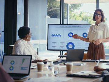 Woman presenting financial analytics to colleagues in a meeting.