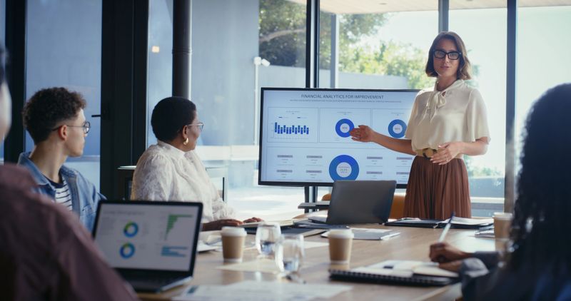 Woman, presentation and monitor for financial analytics, talk and team with feedback for charts at office. Person, speaker and screen with stats, graphs or discussion with revenue review at agency