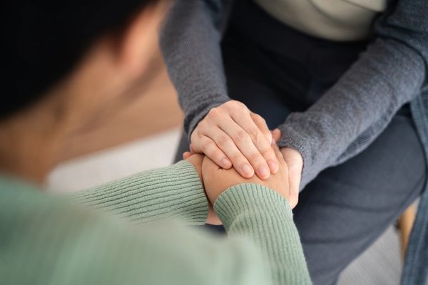 Two people holding hands in a comforting gesture.