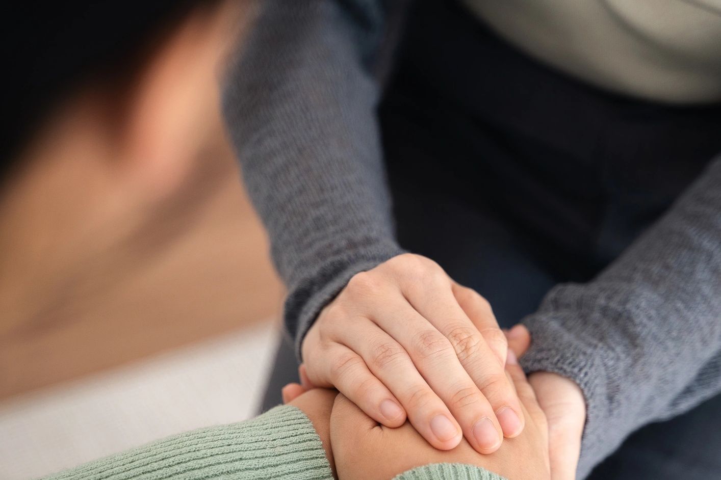 Hands holding gently in a comforting gesture.