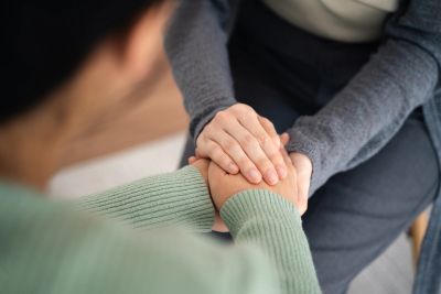 Two people holding hands in comfort.