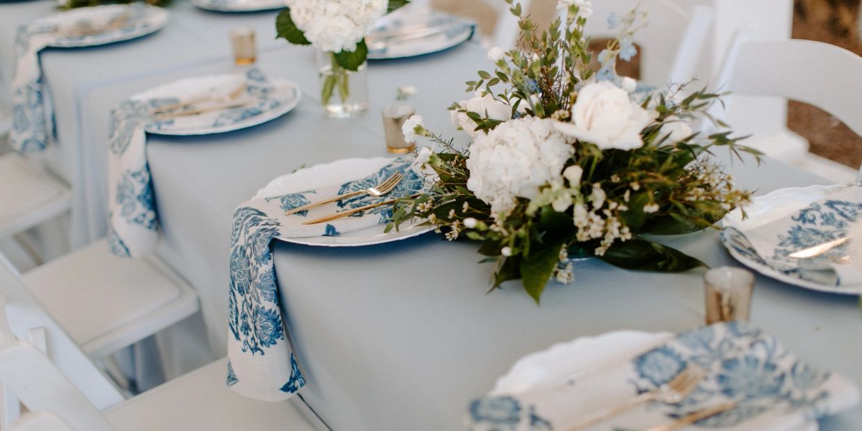 Elegant table setting with blue and white decor and floral centerpiece.