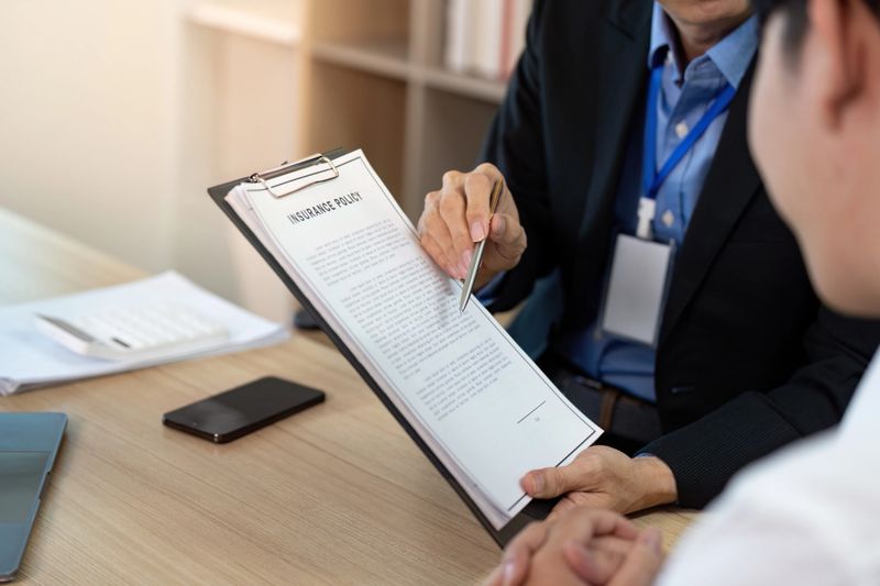 A professional insurance agent explains policy details to a client during a business meeting, emphasizing clarity and understanding.