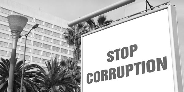 Billboard with bold text saying 'STOP CORRUPTION' against a clear sky.