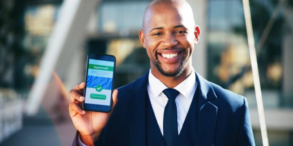 Man smiling, showing phone with approval screen.
