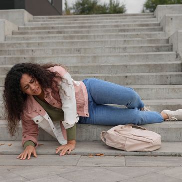Woman injured on stairs, visibly in pain.