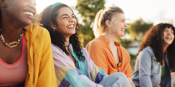 Group of diverse women happily laughing outdoors.