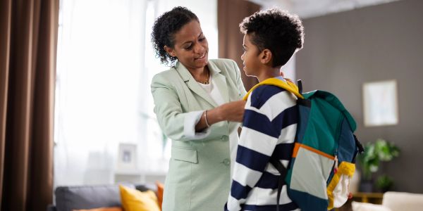 Mother adjusting her son's backpack straps before school.