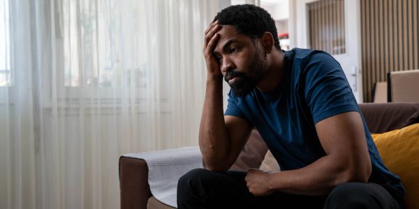 Man sitting on a couch looking stressed.