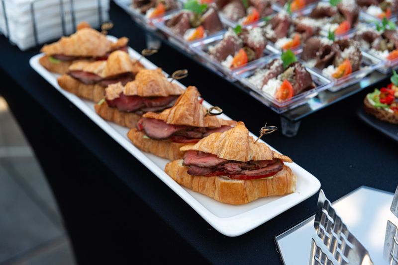 Elegantly arranged croissant sandwiches filled with gourmet ingredients, showcased on a platter. ideal for catering events and culinary presentations.