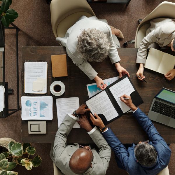 Business meeting with documents and laptops around a table.