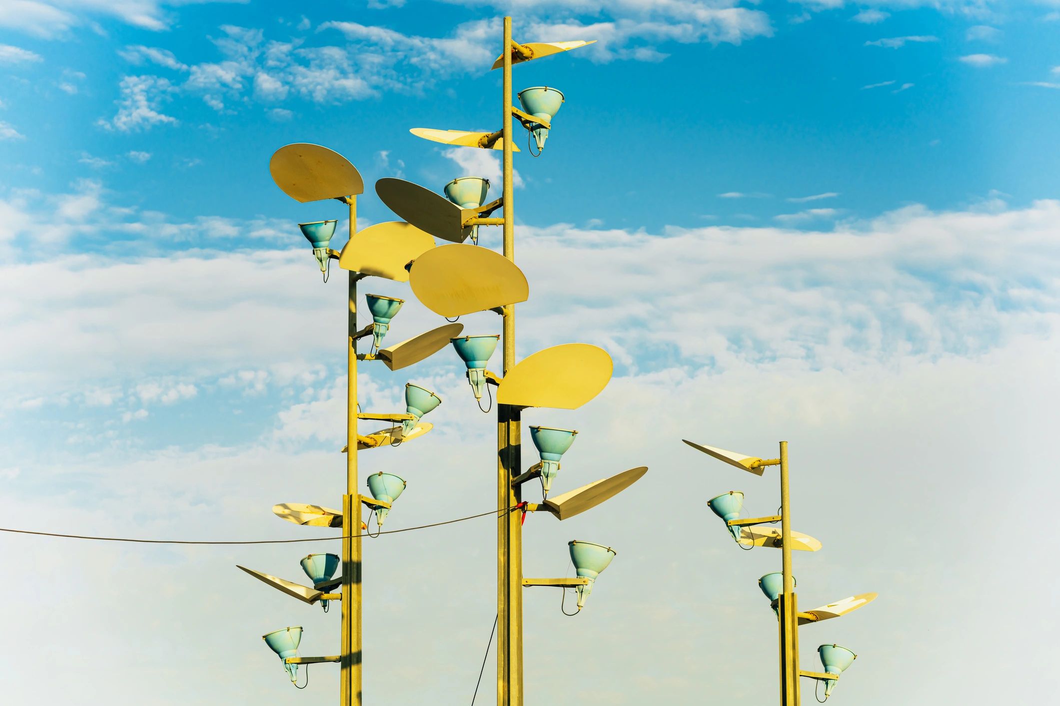 Yellow structures with blue lights against a cloudy sky.