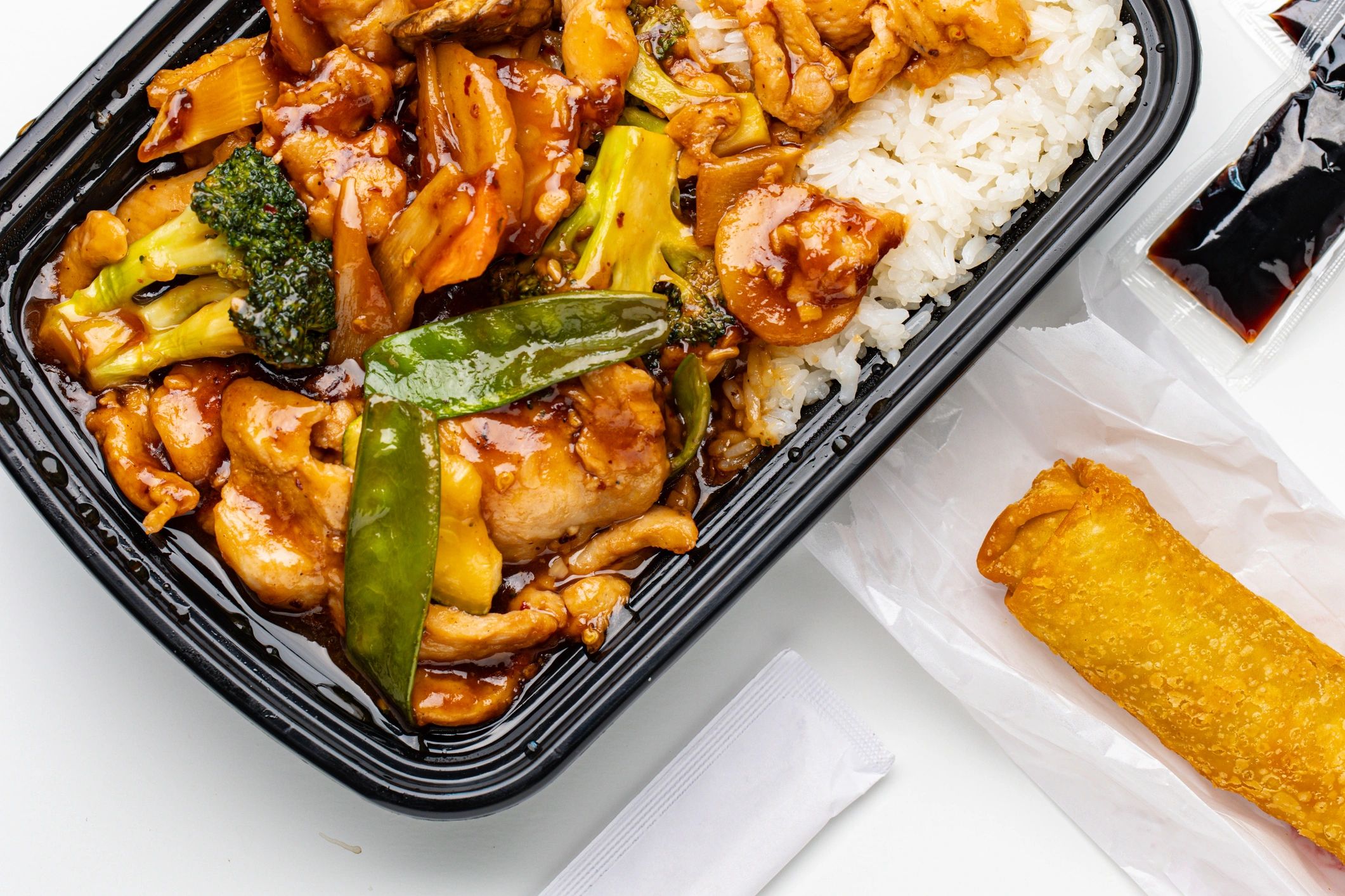 Chinese takeout with chicken, vegetables, white rice, and egg roll.