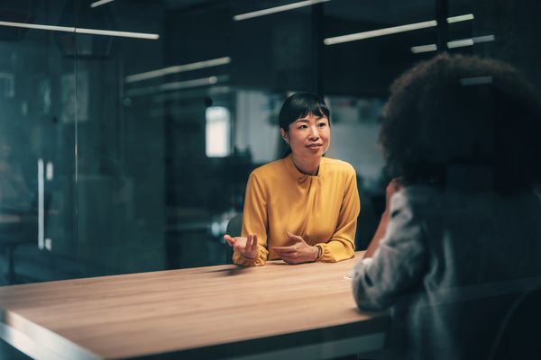 Two women having a discussion at a table in an office.