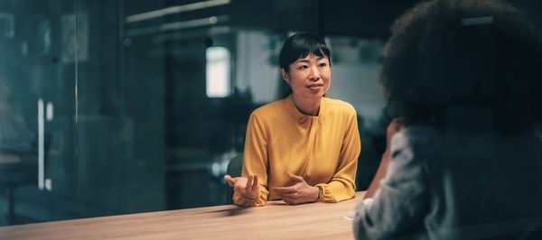 Two women having a discussion at a table in an office.