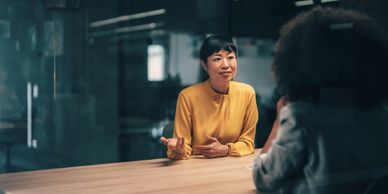 Two women having a discussion at a table in a modern office.