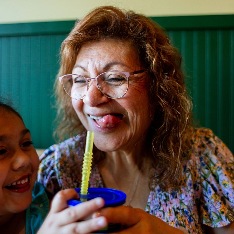 Silly fun moments at a pizza restaurant with a multi generational Latine family with grandma and granddaughter seen in frame.