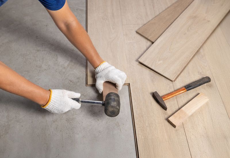 A professional tradesperson installing new flooring in a modern home.