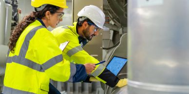 Two engineers in safety gear inspecting machinery.