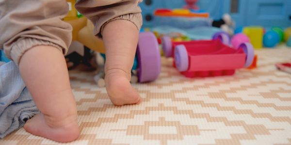 Baby's feet walking on a play mat.
