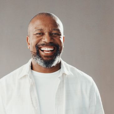 Smiling man in white shirt against a gray background.