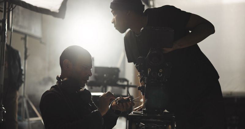 Film, planning and videographer speaking to director in studio for filming or footage update. Conversation, discussion or production with cameraman and producer on set for behind the scenes shooting