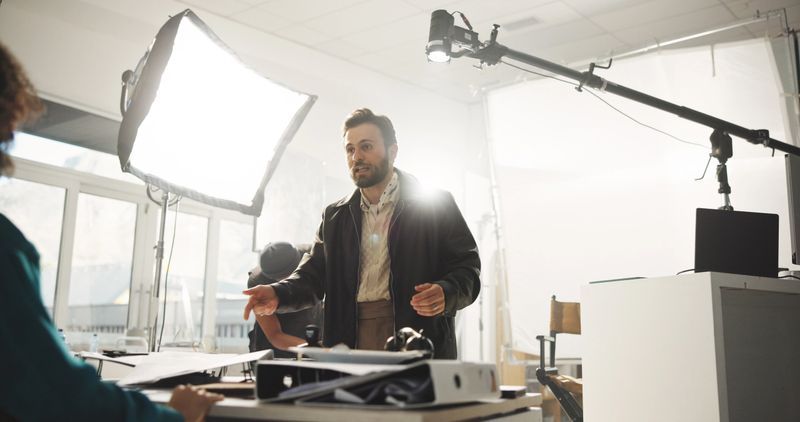 Conversation, creative and director with actress in studio for feedback or instructions on film process. Media, production or videography with producer and talent on set for shoot directions