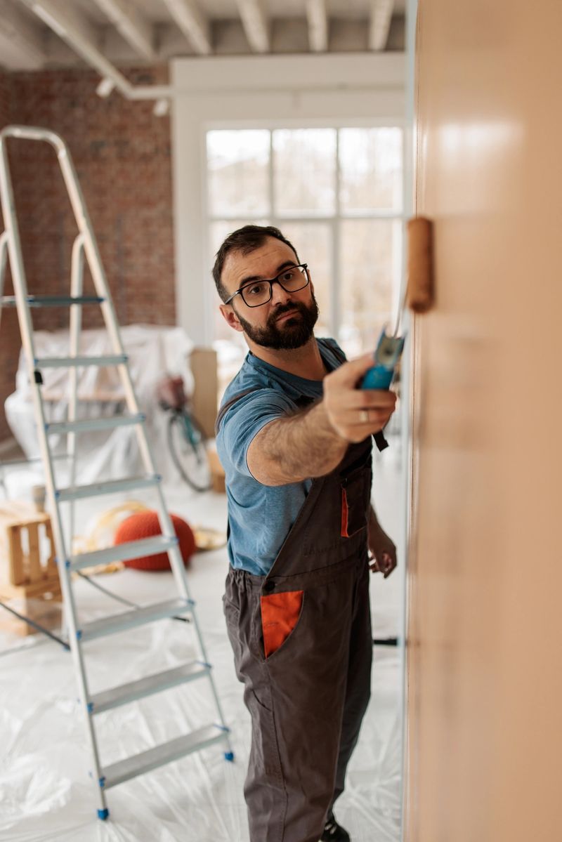 Focused man applying paint on wall surface, creating a brighter and modernized living area as part of home renovation.