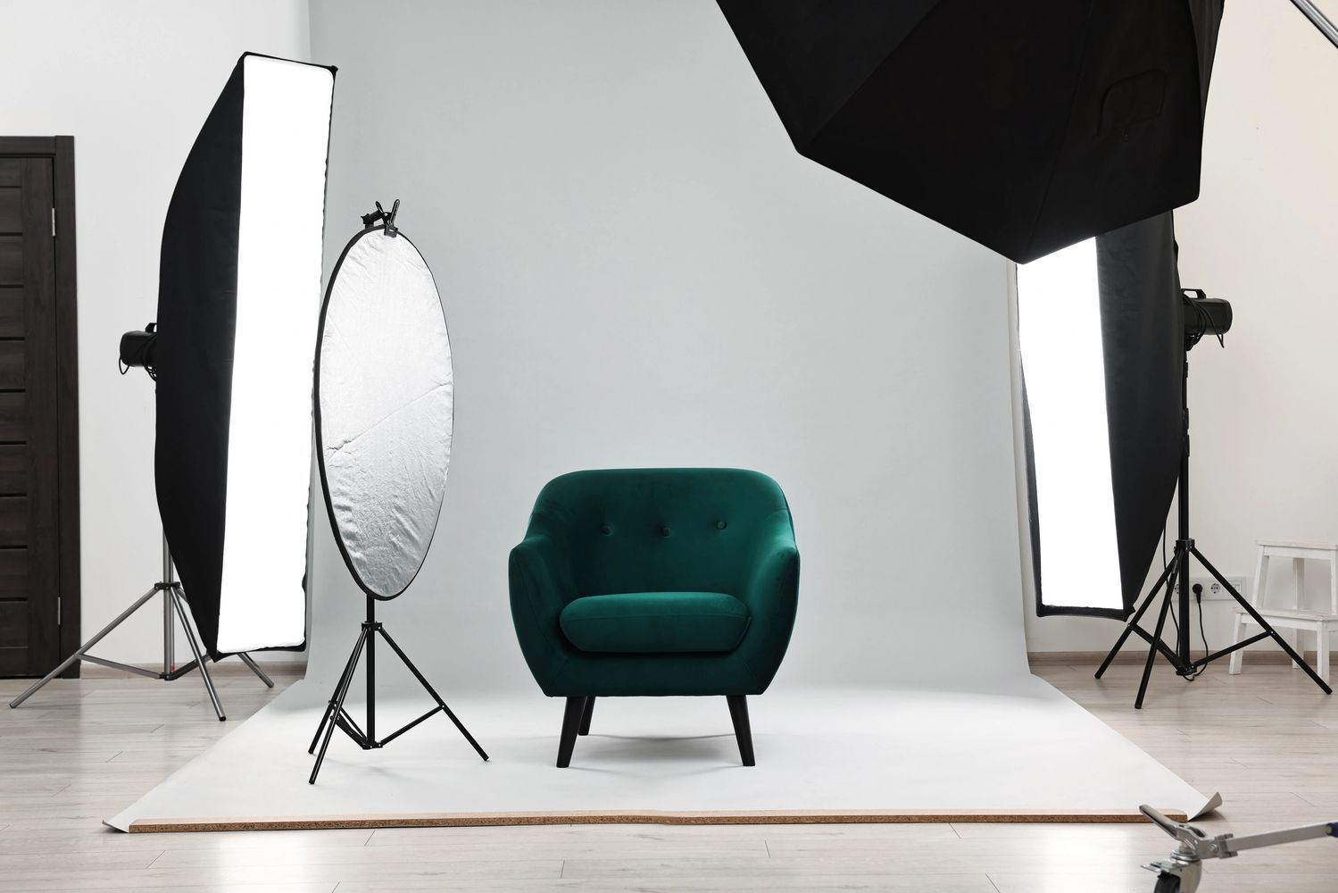 A green armchair in a professional photography studio setup with lighting equipment.