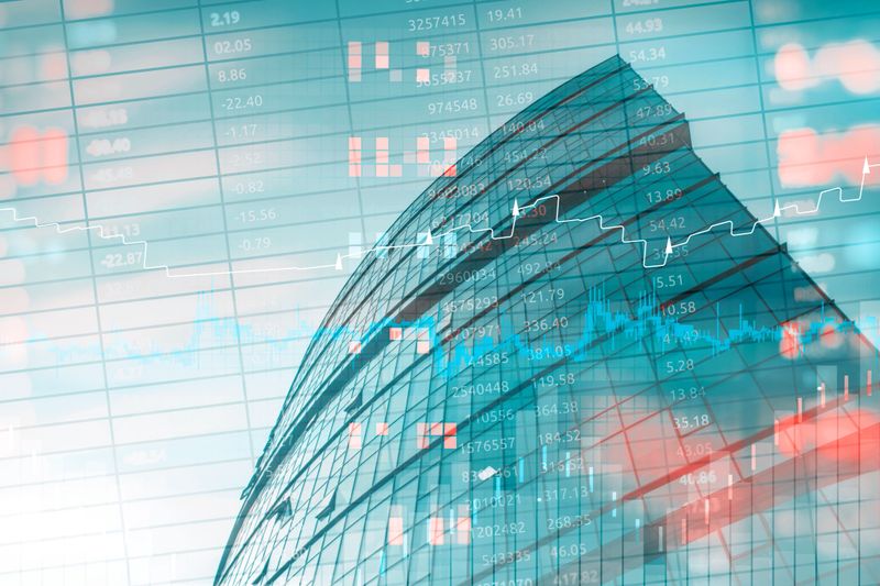 Double exposure of a modern office building with digital stock market data, trading charts, and financial analytics. Abstract background with business skyscraper, candlestick and rising graphs