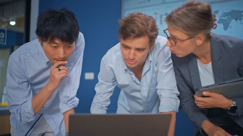 Diverse group of professional businesspeople reviewing marketing analytics on a large interactive screen during a team meeting. Colleagues discussing new user growth, pageviews, and performance metrics in a modern workspace. Concept of teamwork, data-driven strategy, digital marketing, and business intelligence. real people, smart casual businesswear.