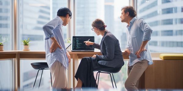 A dual-monitor computer setup with coding and communication apps on a desk.
