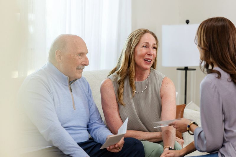 Mature adults discussing financial planning with a consultant.  Home interior setting.