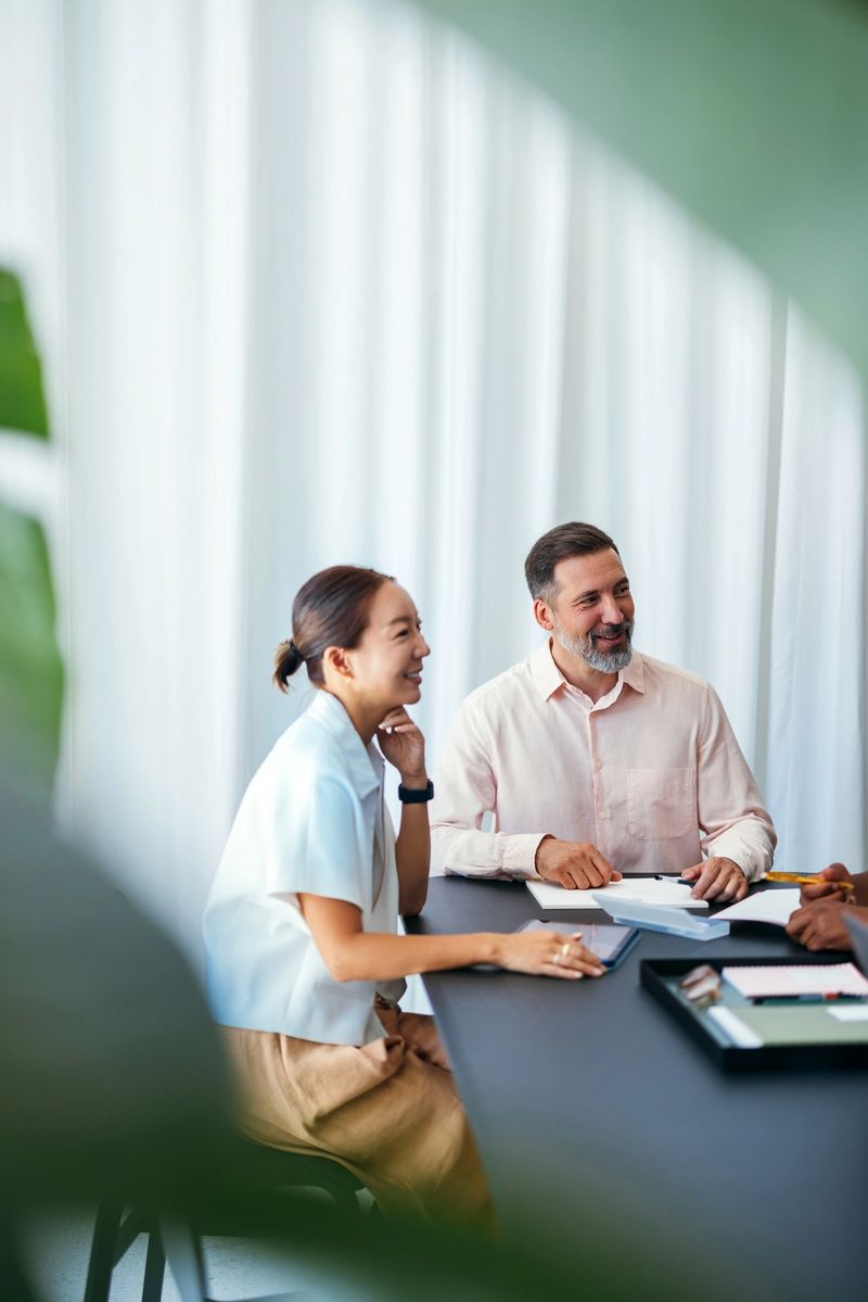 Two coworkers interacting during a workplace meeting, displaying teamwork and camaraderie in a professional setting with a bright, positive atmosphere.