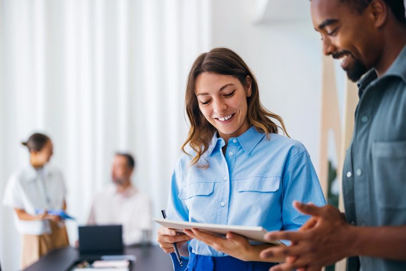 A small team of professionals collaborating energetically around a table in a modern office setting, showcasing teamwork and productive discussions to achieve goals and share ideas in a business context.