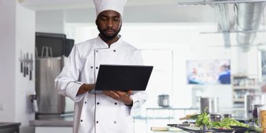 Chef using laptop in kitchen.