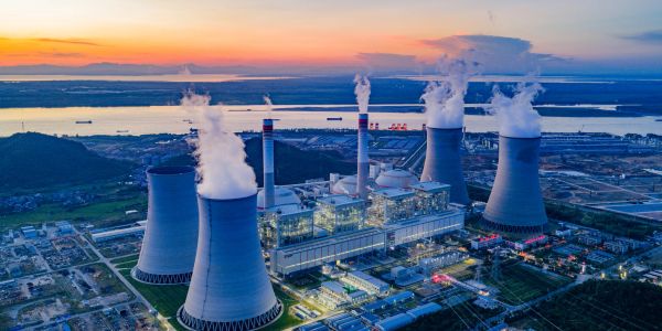Aerial view of a power plant with cooling towers at sunset.