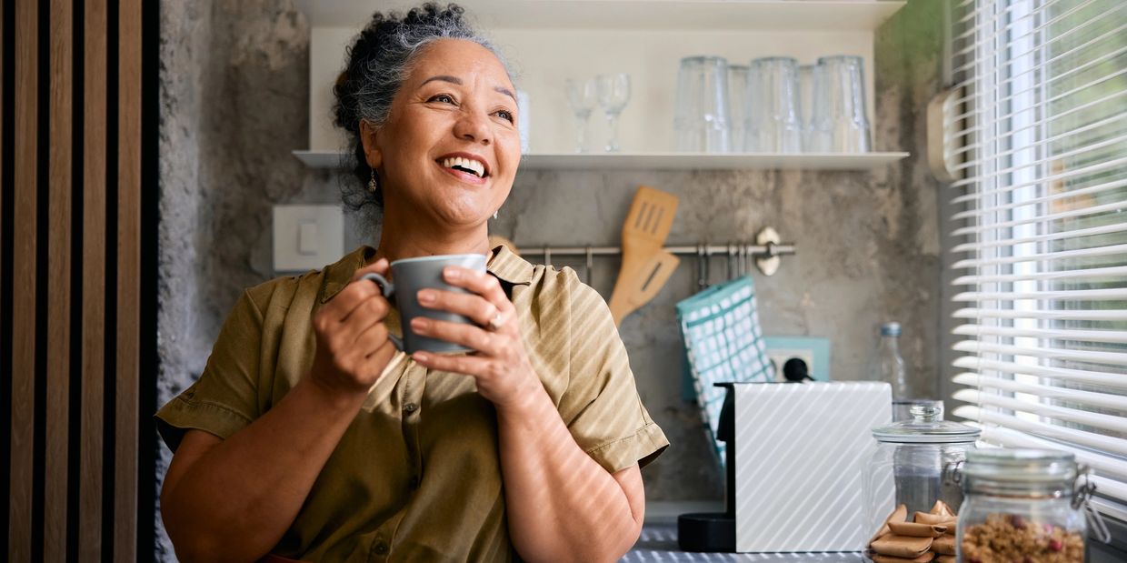 Happy woman enjoying a cup of coffee in a cozy kitchen.