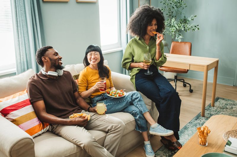Group of friends enjoying healthy snacks together at home, talking, laughing, and having fun.