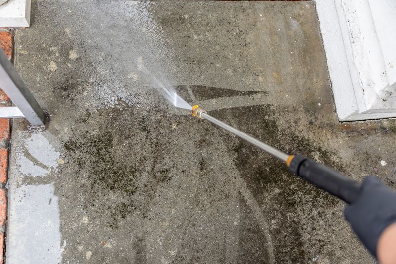 Stock image of a middle aged man powerwashing a home.