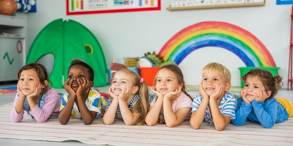 Six children lying on the floor with their chins resting on their hands. Greenbrier Learning Academy Child day care center in Catoosa. 